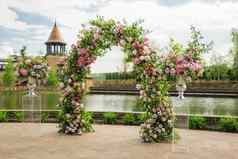 美丽的花拱婚礼仪式花瓶粉红色的玫瑰牡丹婚礼集在户外公园池塘