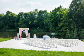 美丽的花拱婚礼仪式花瓶粉红色的玫瑰牡丹婚礼集在户外公园池塘