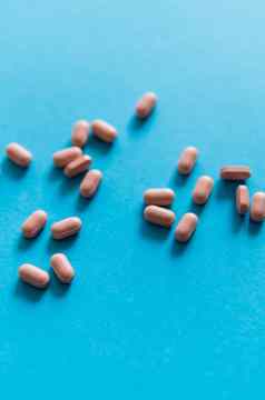 粉红色的药片蓝色的背景医学药物治疗止痛药平板电脑医生药物抗生素维生素治疗药店主题前视图药片分散蓝色的表面