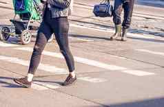 年轻的女人脚穿越城市街