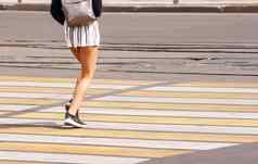 年轻的女人的腿穿越城市街