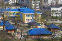 明亮的蓝色的屋顶幼儿园背景灰色的城市高层建筑