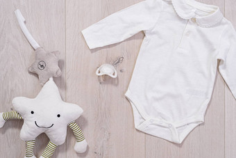 婴儿衣服概念白色西装男孩女孩婴儿奶嘴木背景