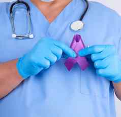 医生蓝色的统一的乳胶手套持有紫色的丝带