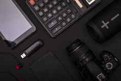 前视图球场黑色的办公室桌子上计算器Usb开车耳机数码单反相机相机无线演讲者最小的黑色的设计概念