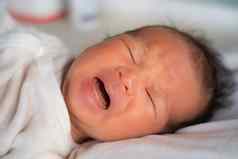 可爱的可爱的新生儿婴儿婴儿说谎床上哭