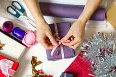 女人包装圣诞节礼物紫罗兰色的包装纸女人手包装圣诞节礼物Diy礼物包装概念