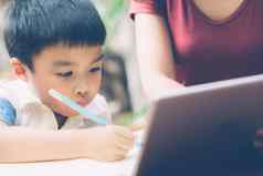 儿子数字平板电脑电脑研究学习互联网在线妈妈。教育首页家庭娱乐妈妈教男孩家庭作业技术生活方式概念