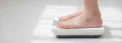 活动腿女人站测量重量规模饮食光着脚特写镜头脚女孩苗条的重量损失测量食物控制健康的护理健康概念横幅网站