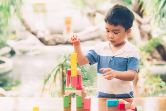 亚洲年轻的男孩玩木块玩具表格有创意的发展享受快乐孩子学习技能活动谜题创造力游戏桌子上首页教育概念