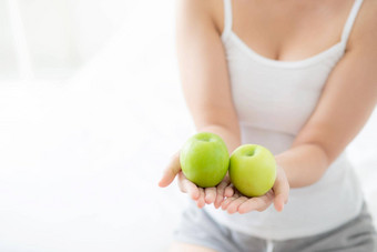特写镜头年轻的亚洲女人持有吃绿色苹果水果卧室首页生活方式营养女孩健康的护理重量损失健康健康概念