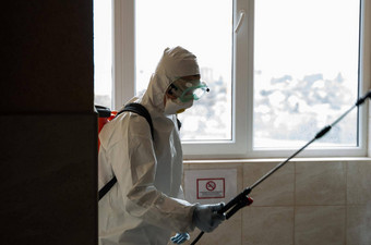 乌克兰基辅男人。白色保护西装面具消毒室内表面内部建筑冠状病毒疫情感染预防控制疫情