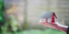 成人手持有红色的房子模型在户外概念首页财产房地产文本空间