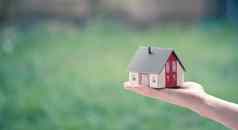 成人手持有红色的房子模型在户外概念首页财产房地产文本空间