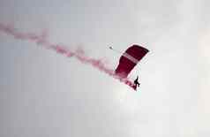 轮廓降落伞特技无重点模糊的滑翔空气红色的烟小道空气展览