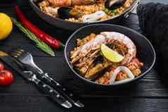 传统的西班牙语海鲜西班牙海鲜饭锅碗大米豌豆虾贻贝鱿鱼黑色的木木板