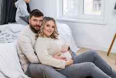快乐家庭概念丈夫拥抱肚子怀孕了妻子坐着地板上室内生活房间沙发