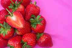 草莓甜蜜的红色的水果seed-studded表面特写镜头纹理红色的浆果心形的水果粉红色的织物