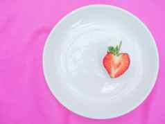 单红色的心草莓甜蜜的水果特写镜头纹理红色的浆果心形的水果一半减少白色板粉红色的织物背景