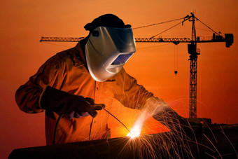 焊接工人焊接钢结构建设起重机建筑建设网站日落建设工业工作概念