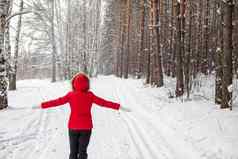 女孩红色的夹克走白雪覆盖的森林
