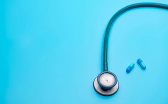 蓝色的胶囊药片模糊绿色听诊器蓝色的背景复制空间健康检查心脏病学医生设备心跳测试医疗保健医疗背景诊断工具