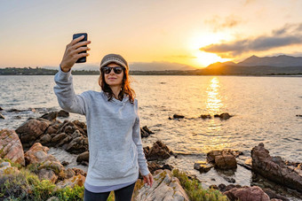 年轻的高加索人女人采取自画像相机太阳镜羊毛他海洋海度假<strong>胜地</strong>日落黎明只有女旅行者有趣的分享照片社会网络