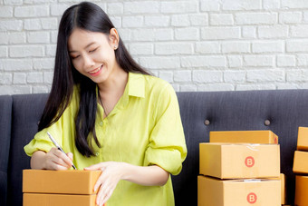 年轻的亚洲女人写作地址包裹盒子首页交付订单客户航运物流商人在线卖方业务老板锻造在线购物电子商务