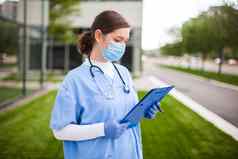 女国民健康保险制度医生持有蓝色的剪贴板站医院诊所街入口