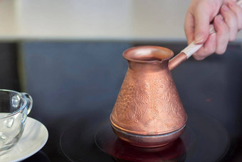 铜土耳其人酝酿咖啡站微晶玻璃板女人的手持有处理土耳其人使咖啡土耳其人