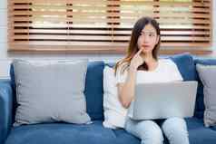 美丽的年轻的亚洲女人工作移动PC电脑思考的想法沙发首页自由女孩坐着沙发上笔记本互联网生活房间人生活方式概念
