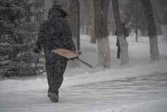 工作男人。市政服务雪铲走路风暴暴雪降雪冬天坏天气城市极端的冬天天气条件北