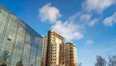 城市建筑灰色的多层建筑玻璃外观蓝色的天空云反映了玻璃