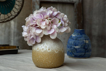 花束紫色的花白色黄色的手工制作的陶瓷花瓶古董风扇白色变形表格布水泥墙
