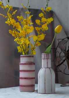 花束黄色的花手工制作的陶瓷花瓶古董风扇白色变形表格布水泥墙