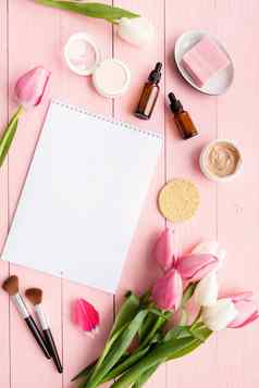 前视图化妆品粉红色的白色郁金香日历记事本模拟平躺粉红色的木背景