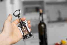 金属螺旋男人的手瓶红色的酒背景光白色厨房酒情人酒开瓶器