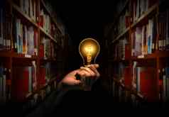手持有光灯泡书架上图书馆背景概念的想法阅读书知识搜索的想法