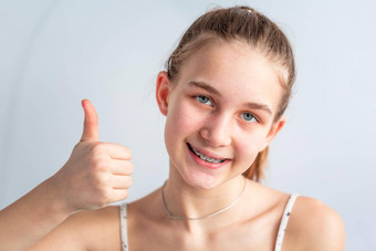 十几岁的女孩微笑矫正括号显示拇指女孩牙套牙齿
