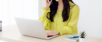 年轻的亚洲业务女人工作形式<strong>首页</strong>办公室调用电话成功<strong>首页</strong>女商人移动PC电脑桌子上女会说话的智能<strong>手机</strong>工作场所沟通概念