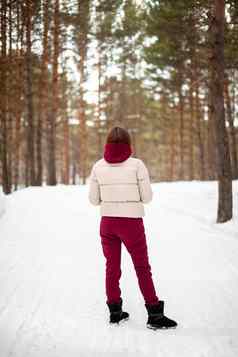 冬天走白雪覆盖的森林女孩红色的连身裤