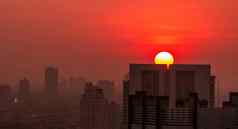 城市景观早....日出天空空气污染细灰尘封面城市城市景观拥挤的住宅建筑城市日出大红色的太阳烟雾空气不健康的