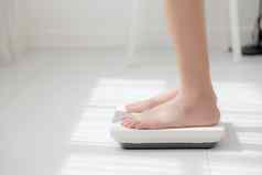生活方式活动腿女人站测量重量规模饮食光着脚特写镜头脚女孩苗条的重量损失测量食物控制营养健康的护理健康概念