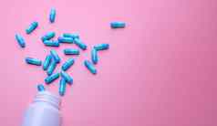 蓝色的胶囊药片传播白色塑料药物瓶粉红色的背景药店横幅在线药店止痛药医学抗生素药物电阻概念制药行业