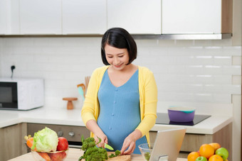 怀孕了女人切割西兰花新鲜的绿色沙拉女准备美味的有机晚餐<strong>首页</strong>