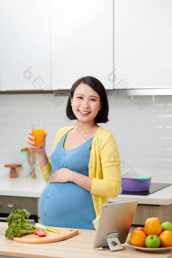 怀孕了女人玻璃橙色汁厨房