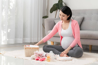 美丽的怀孕了亚洲女人包装准备婴儿衣服篮子准出生婴儿