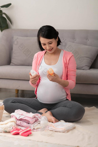 美丽的怀孕了亚洲女人笔写作列表笔记本包装准备婴儿衣服篮子