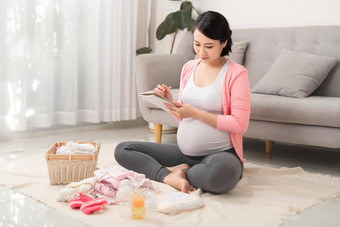 快乐的怀孕了准备婴儿衣服使列表准备好了婴儿交付