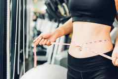 美丽的女人磁带测量腰身体苗条的锻炼健身健身房